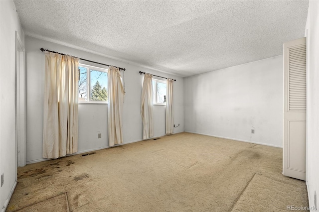 unfurnished room with visible vents, carpet floors, and a textured ceiling