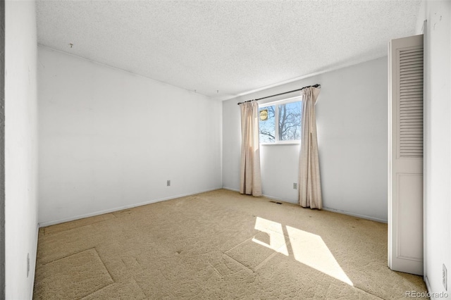 unfurnished room with visible vents, a textured ceiling, and carpet flooring