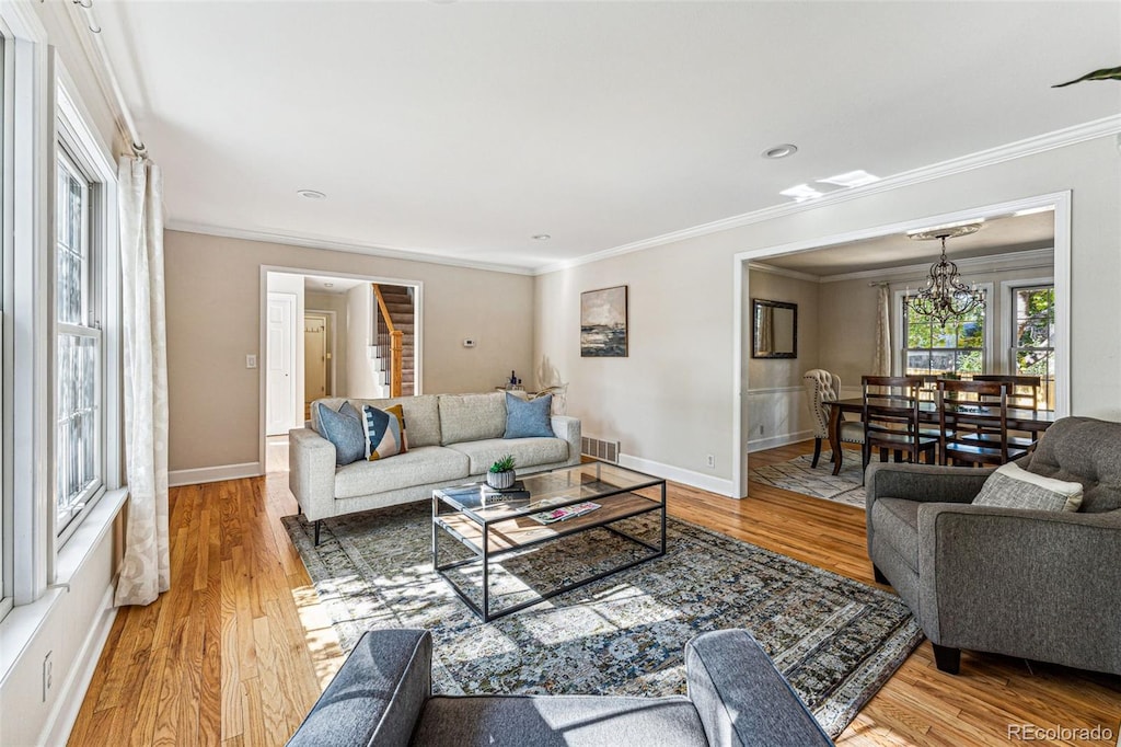 living room with ornamental molding, hardwood / wood-style floors, and a chandelier