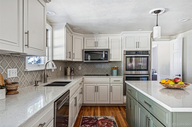 kitchen featuring stainless steel appliances, dark hardwood / wood-style flooring, white cabinets, hanging light fixtures, and sink