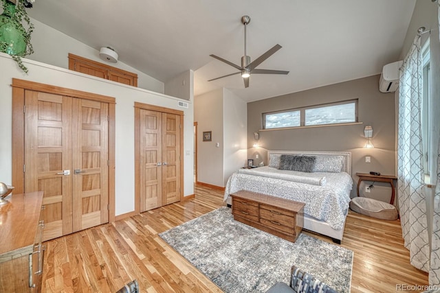 bedroom with hardwood / wood-style floors, vaulted ceiling, an AC wall unit, and ceiling fan