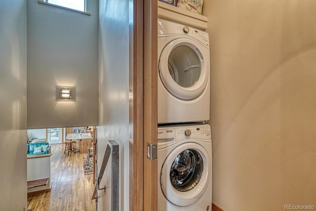 clothes washing area featuring stacked washer and dryer and hardwood / wood-style floors