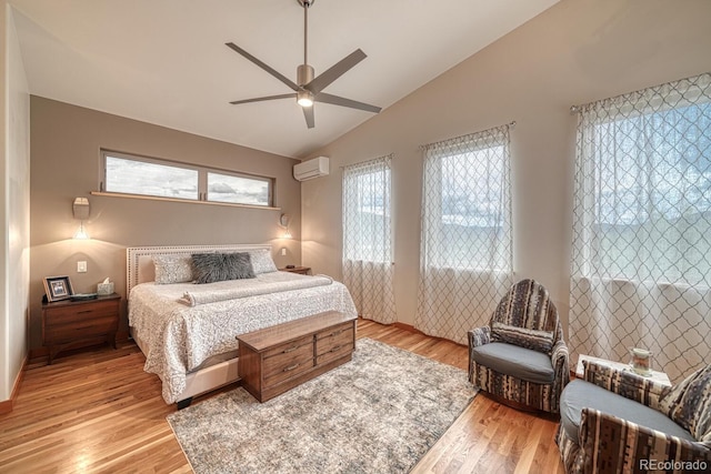 bedroom with ceiling fan, lofted ceiling, a wall mounted AC, and light hardwood / wood-style flooring