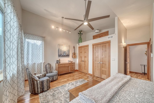 bedroom with multiple closets, ceiling fan, and light wood-type flooring