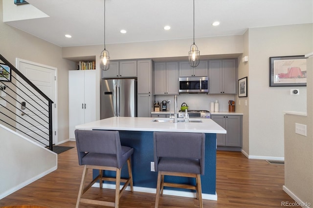 kitchen with dark wood-style floors, light countertops, backsplash, gray cabinetry, and appliances with stainless steel finishes