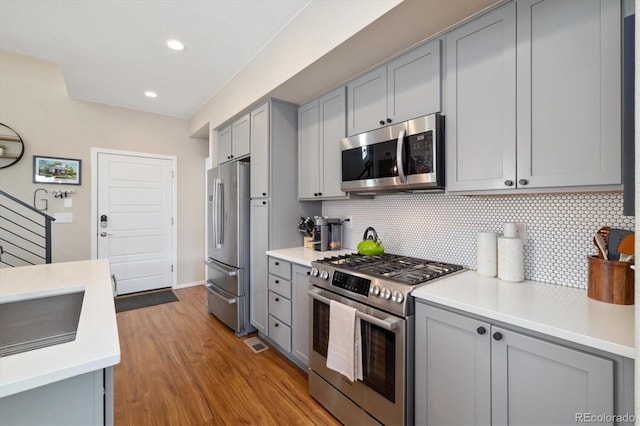 kitchen with appliances with stainless steel finishes, gray cabinets, light countertops, and tasteful backsplash