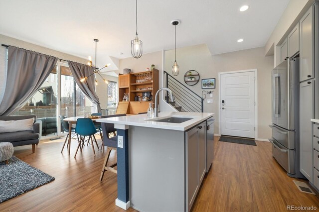 kitchen featuring appliances with stainless steel finishes, wood finished floors, light countertops, gray cabinetry, and a sink