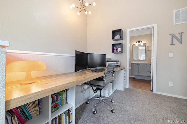 carpeted office space with a chandelier, visible vents, and baseboards