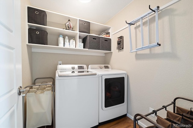 clothes washing area with laundry area, baseboards, wood finished floors, and washing machine and clothes dryer