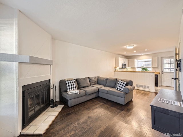 living room featuring a tiled fireplace and light hardwood / wood-style flooring