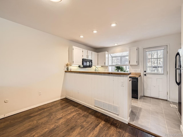 kitchen with black appliances, white cabinetry, hardwood / wood-style flooring, and kitchen peninsula