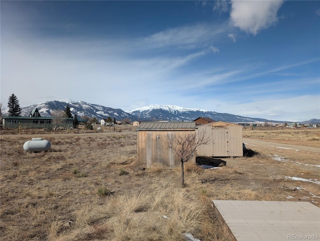 view of yard featuring a shed, a mountain view, and a rural view