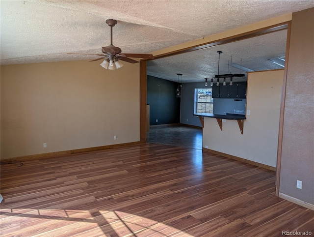 unfurnished living room featuring dark hardwood / wood-style flooring, ceiling fan, lofted ceiling, and a textured ceiling