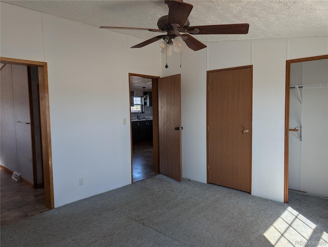 unfurnished bedroom with ceiling fan, carpet flooring, sink, and a textured ceiling