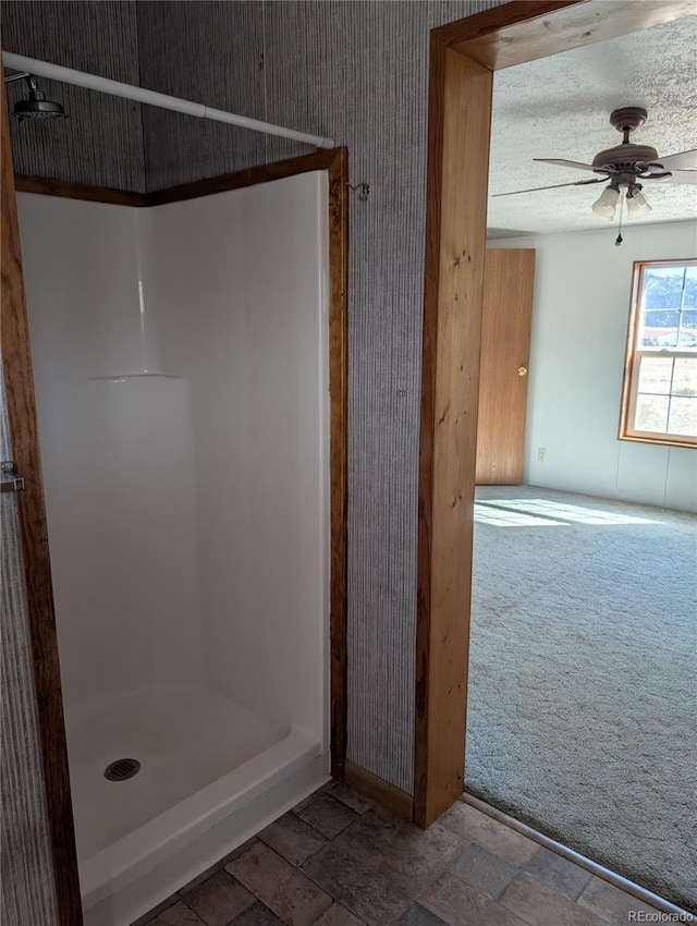 bathroom with ceiling fan, a textured ceiling, and a shower