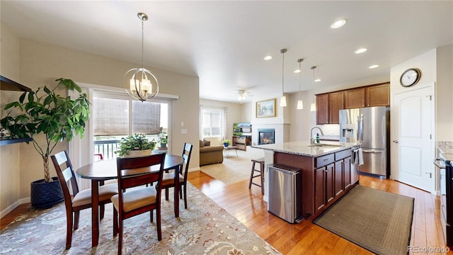 17114 Elati St, Broomfield, CO 80023 - kitchen featuring stainless steel refrigerator with ice dispenser, a glass covered fireplace, light wood finished floors, light stone countertops, and open floor plan
