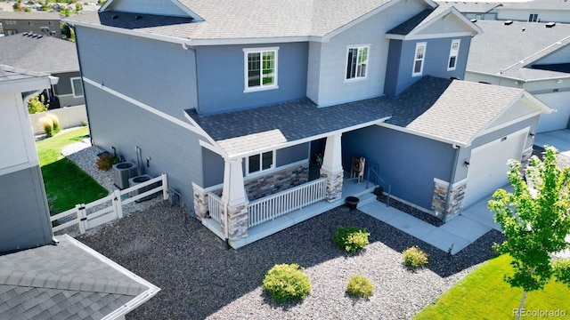 back of property featuring central air condition unit, a garage, and covered porch