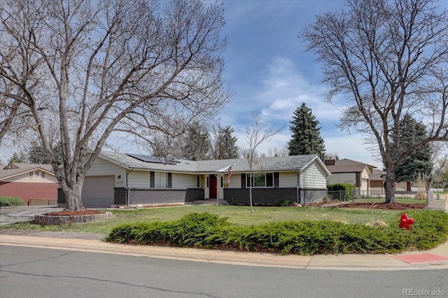 ranch-style home with driveway, solar panels, a front yard, fence private yard, and an attached garage