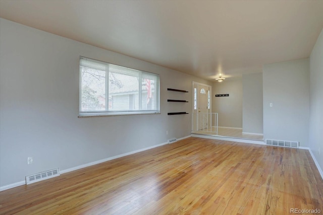 empty room featuring visible vents, baseboards, and wood finished floors