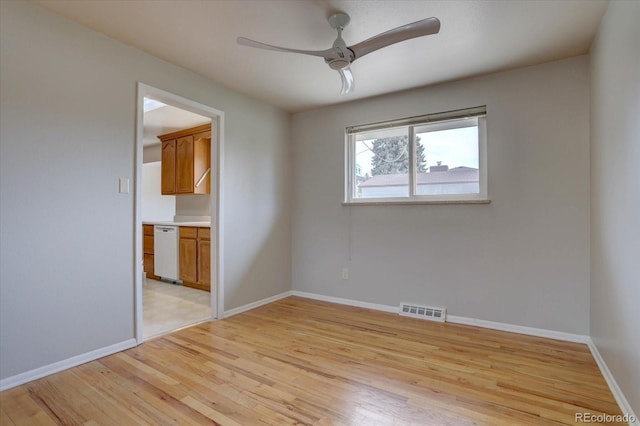spare room featuring visible vents, light wood-style floors, ceiling fan, and baseboards