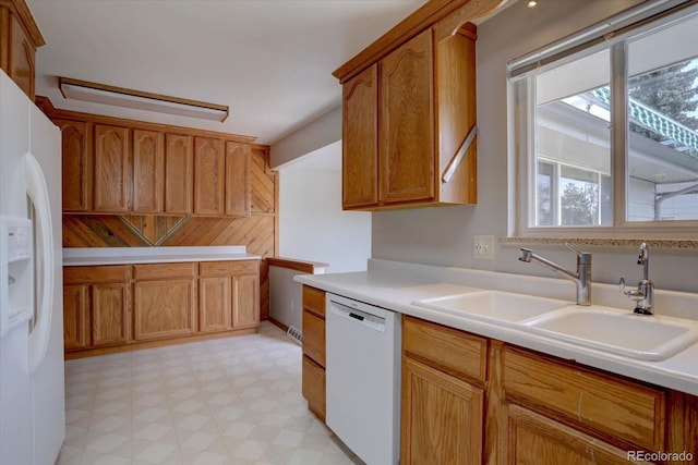 kitchen featuring brown cabinetry, white appliances, light floors, light countertops, and a sink