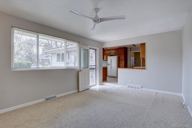 unfurnished room featuring a ceiling fan, light colored carpet, visible vents, and baseboards