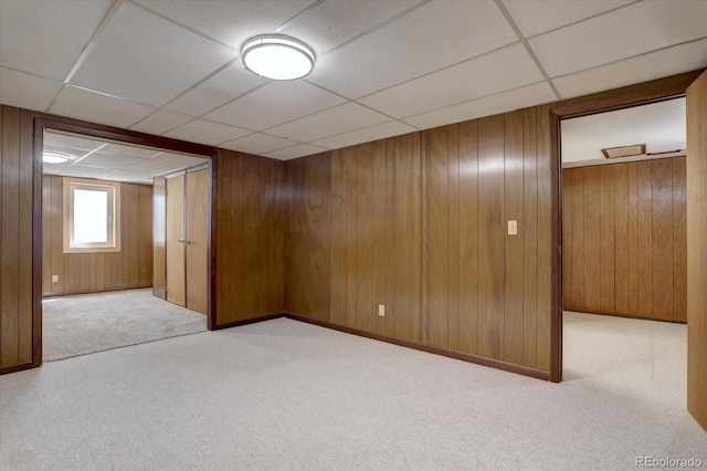 interior space featuring carpet floors, wood walls, and a paneled ceiling