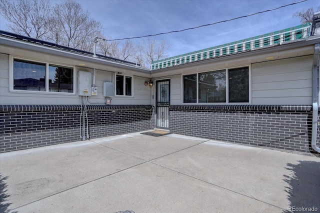 exterior space featuring brick siding and a patio area