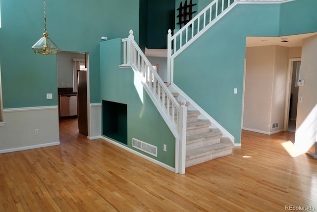 interior space featuring a towering ceiling, visible vents, and wood finished floors