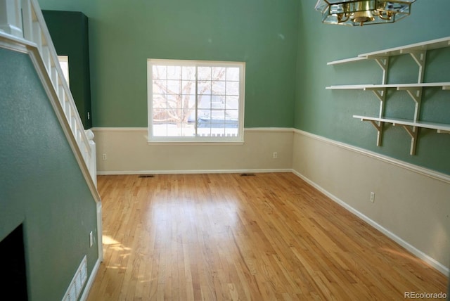 empty room with light wood-style floors, baseboards, and a chandelier