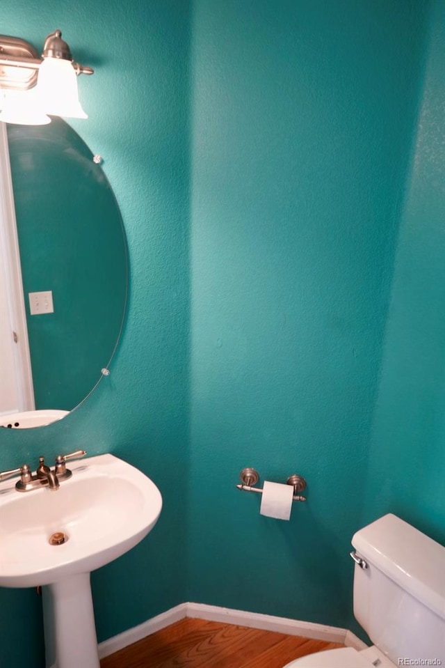 bathroom featuring baseboards, a sink, toilet, and wood finished floors