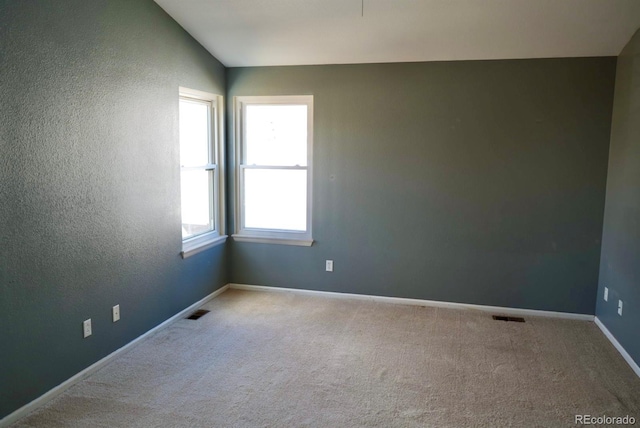 spare room with lofted ceiling, baseboards, visible vents, and carpet flooring