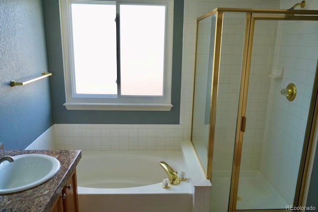 full bathroom with a textured wall, a shower stall, vanity, and a bath