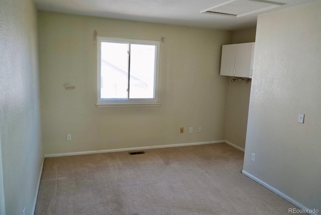 spare room featuring light carpet, baseboards, visible vents, and attic access