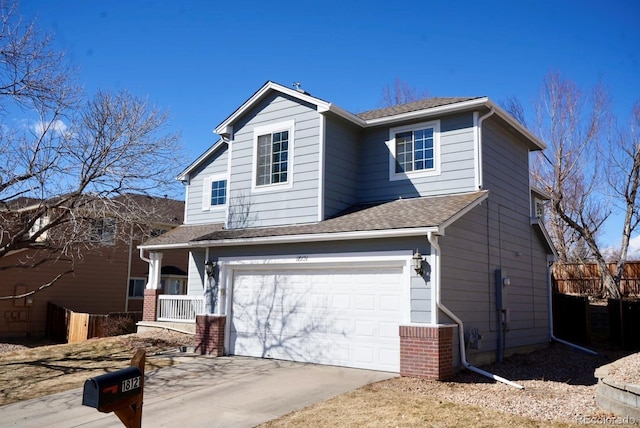 traditional home featuring a garage, concrete driveway, fence, and a shingled roof