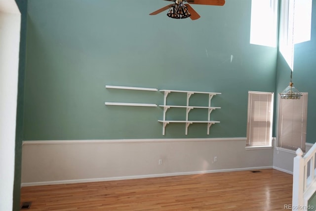 unfurnished room with light wood-style floors, baseboards, visible vents, and a ceiling fan