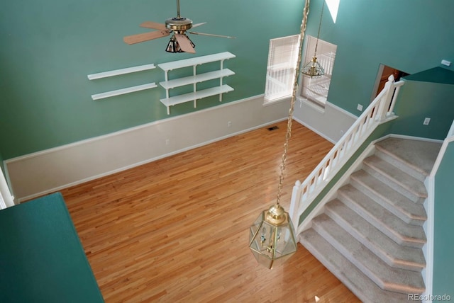 staircase featuring ceiling fan, wood finished floors, and baseboards