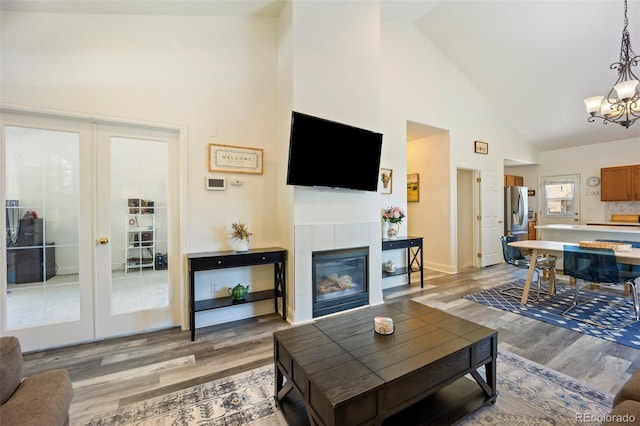 1884 Asoka St, Strasburg, CO 80136 - living area with high vaulted ceiling, light wood-style flooring, french doors, a chandelier, and a tile fireplace
