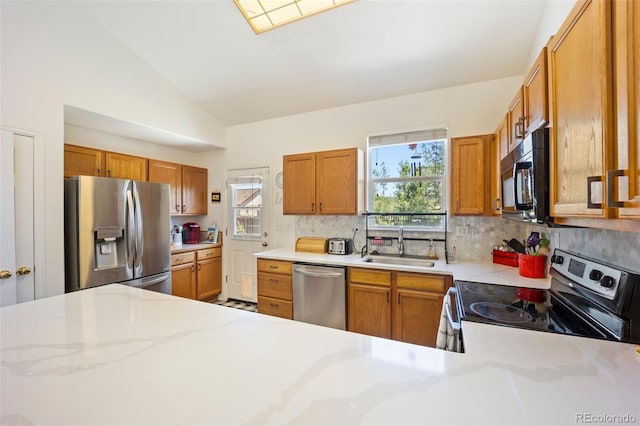 1884 Asoka St, Strasburg, CO 80136 - kitchen featuring stainless steel appliances, decorative backsplash, lofted ceiling, and brown cabinetry