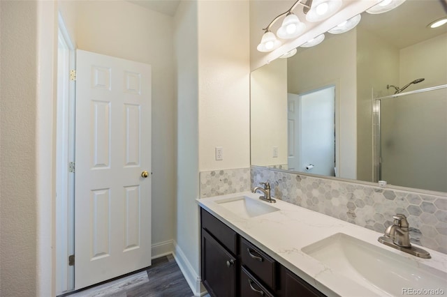 1884 Asoka St, Strasburg, CO 80136 - bathroom with double vanity, a shower stall, wood finished floors, and decorative backsplash