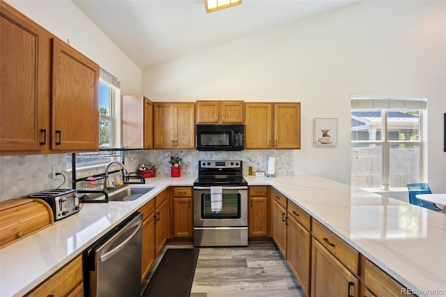 1884 Asoka St, Strasburg, CO 80136 - kitchen featuring appliances with stainless steel finishes, brown cabinets, light wood finished floors, high vaulted ceiling, and backsplash