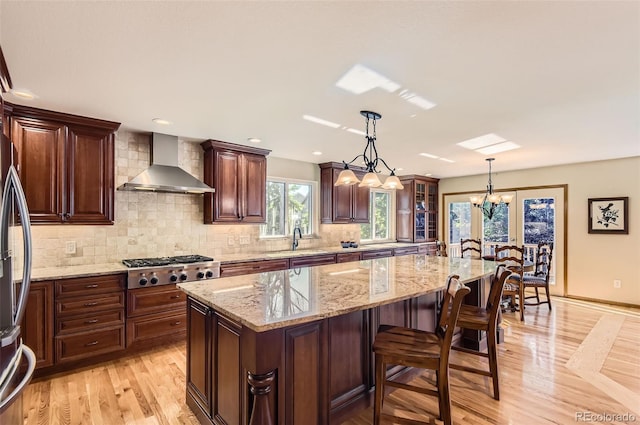 7855 Arundel Ln, Lone Tree, CO 80124 - kitchen with wall chimney range hood, light wood-style flooring, decorative backsplash, a chandelier, and recessed lighting