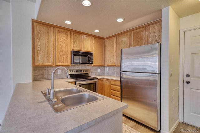 kitchen with kitchen peninsula, appliances with stainless steel finishes, tasteful backsplash, sink, and light brown cabinets