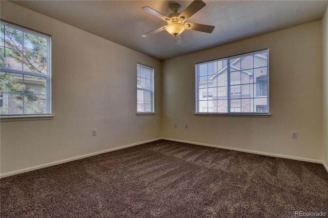 carpeted empty room with ceiling fan and a wealth of natural light