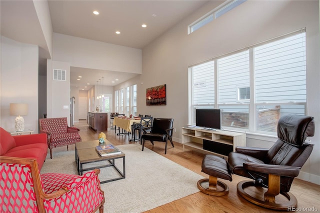 living room with light wood-type flooring and a high ceiling