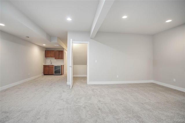 unfurnished living room featuring beverage cooler, sink, light colored carpet, and beam ceiling