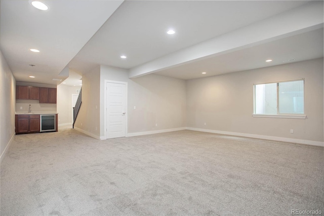 unfurnished living room featuring beamed ceiling, light carpet, sink, and wine cooler