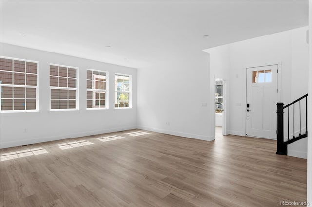 213 Washington St, Erie, CO 80516 - unfurnished living room featuring plenty of natural light, stairway, wood finished floors, and baseboards