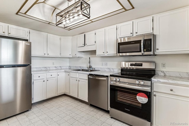 kitchen featuring appliances with stainless steel finishes, white cabinetry, sink, and a notable chandelier