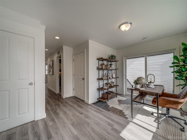 office with light hardwood / wood-style floors and crown molding